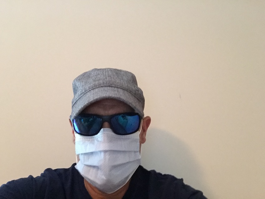 Mike wearing white mask, sunglasses, and a hat