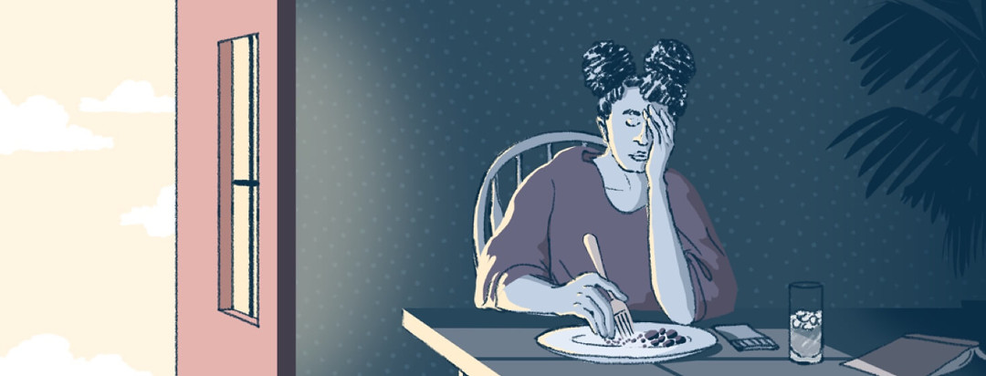 woman sitting at a table in the dark looking very tired and fatigued