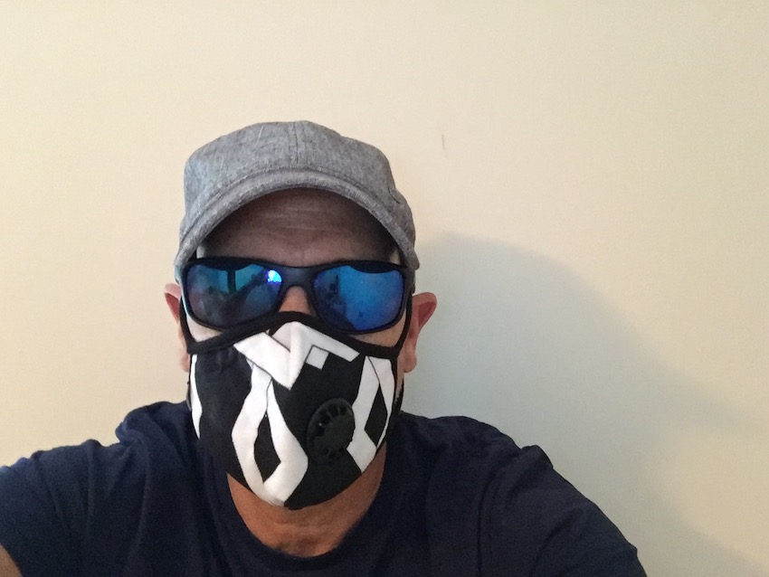 Mike wearing black and white mask, sunglasses, and a hat