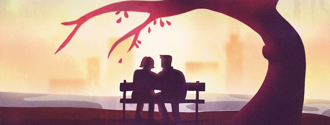 A couple sitting on a park bench at sunset