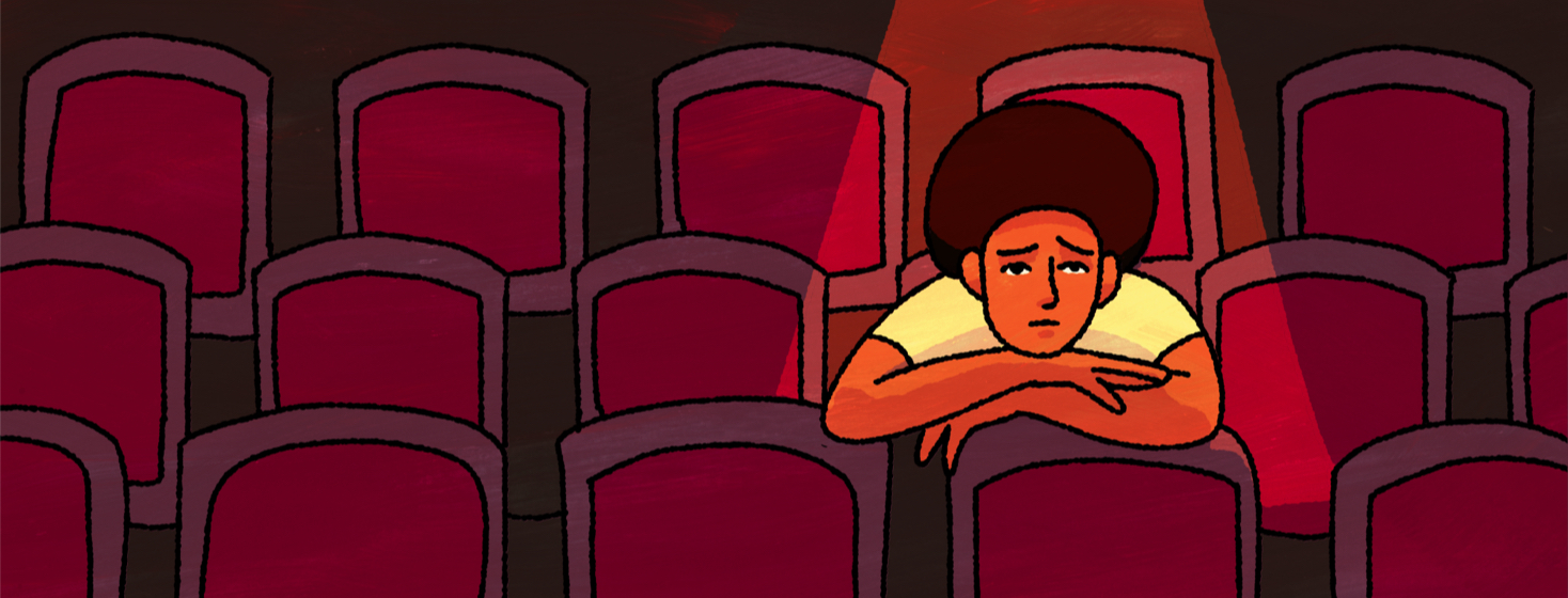 A sad person sits in an empty theater with a spotlight on them