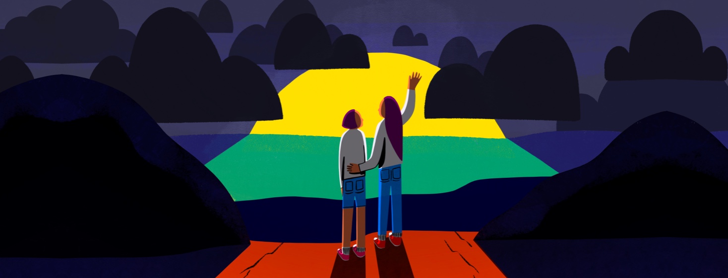 Two women stand and watch the sunrise behind dark clouds